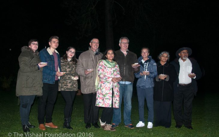 A group of people standing together holding a small dish of petals.