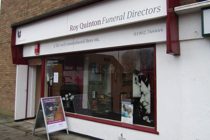 Picture of Ro Quinton Funeral Directors. A white building with dark red trim.