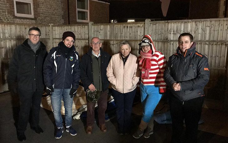 A group of people standing together all bundled up in warm clothes.