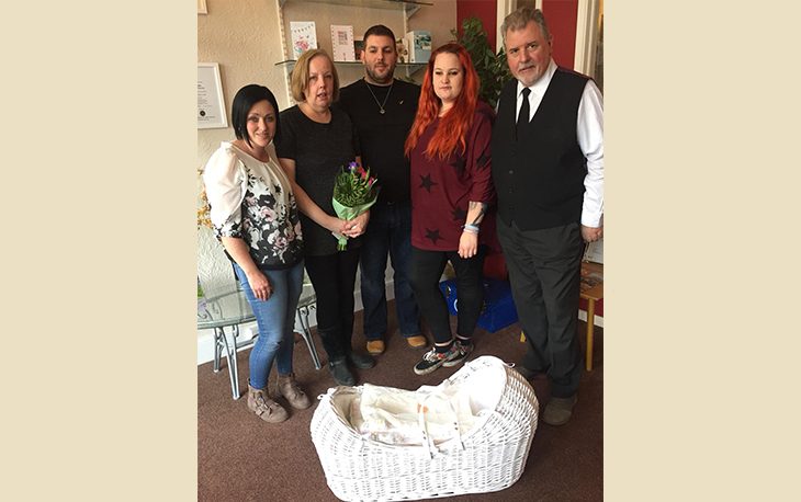 Picture of family standing in front of cuddle cot donation made.