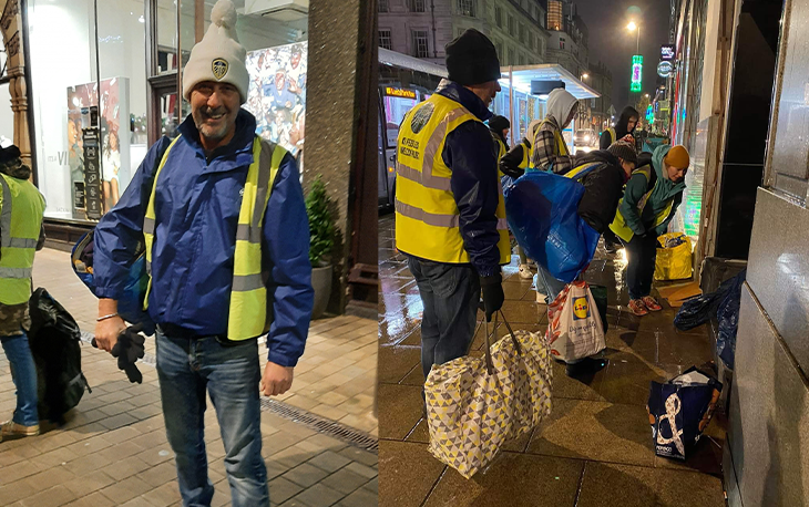 A man wearing a high vis vest handing essentials to homeless.