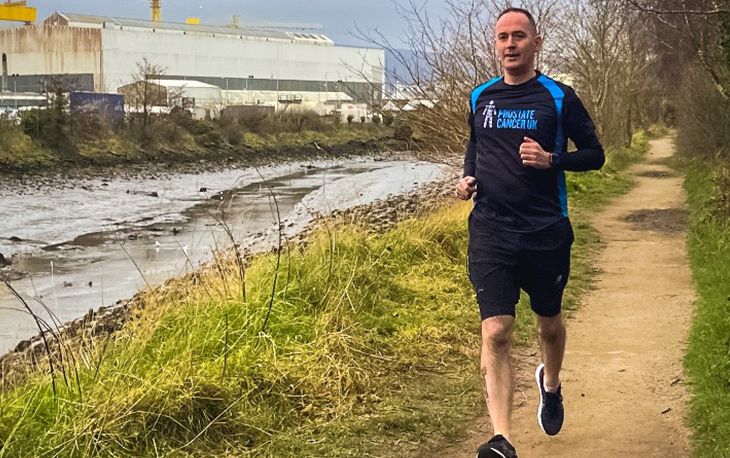 A man running on a trail near a river.