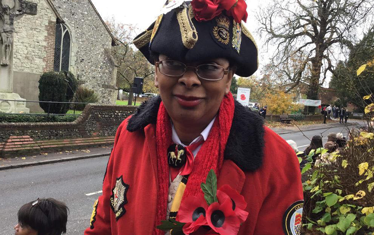 Women dressed in red town crier uniform with black tricorn hat.