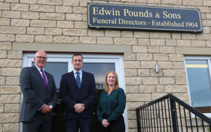 A group of people standing in front of Funeral service Edwin Pounds & Sons.