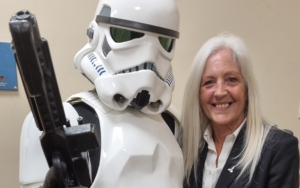 A lady posing for a picture next to a stormtrooper.