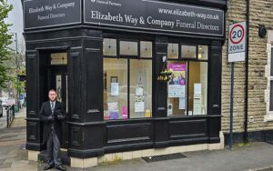 New funeral director Ben McCutcheon in front of black wall.